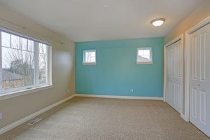 bedroom with light blue accent wall and 2 closet doors