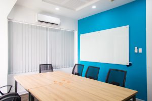 small meeting room with a bright blue wall behind a white board