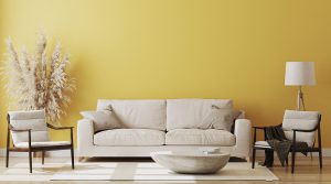 bright yellow wall behind two chairs and couch inside of a home