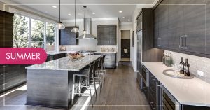 A bright kitchen with dark grey wood cabinets and marble white and grey countertops.
