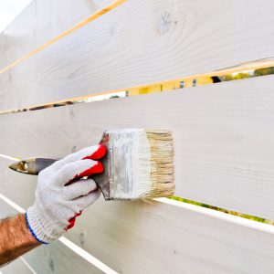 hand painting a fence white