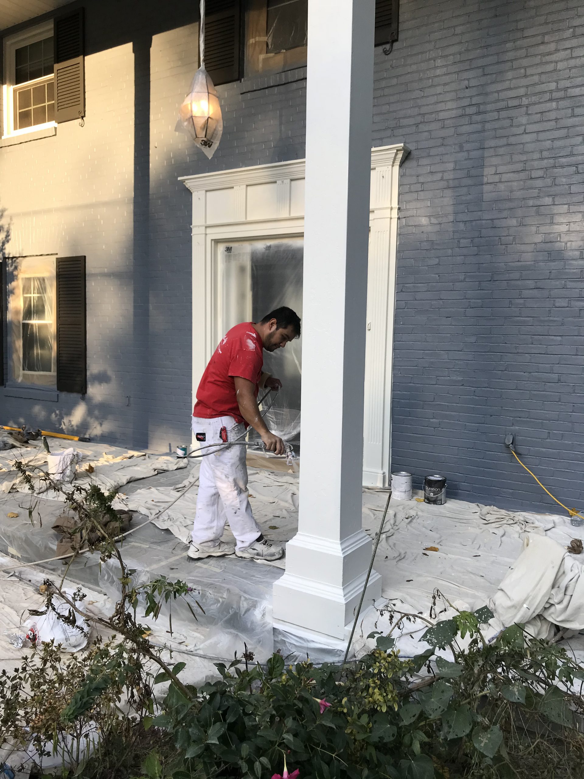 painter painting a column on a house white